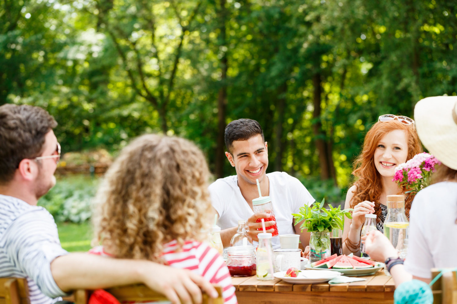 Young people laughing, eating and talking on a sunny day in the garden
